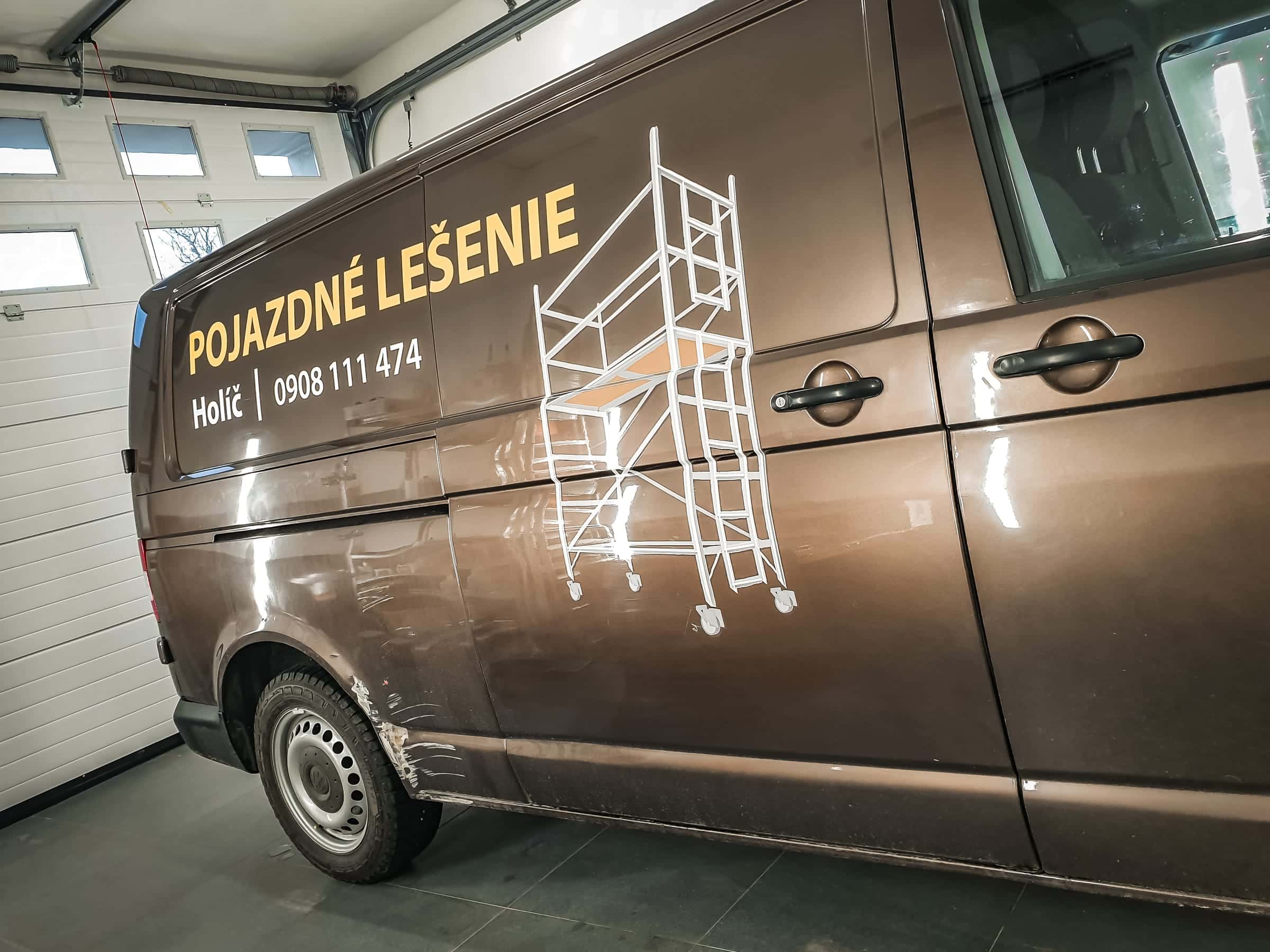 Hnedá dodávka VW s polepom Pojazdné lešenie Holíč a kresbou lešenia v dielni