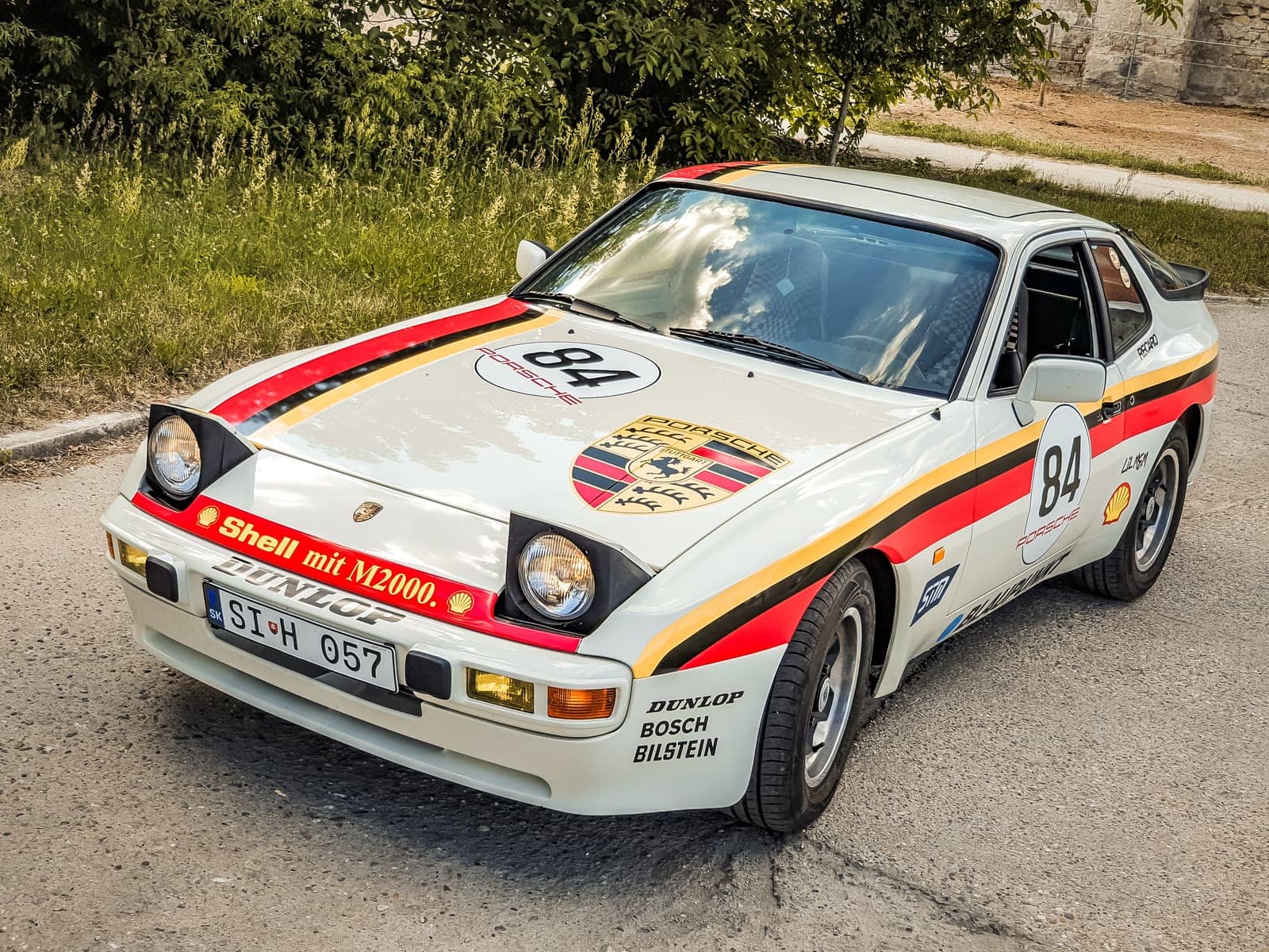 Biele Porsche 944 s retro závodným polepom, štartovým číslom 84 a nápismi sponzorov