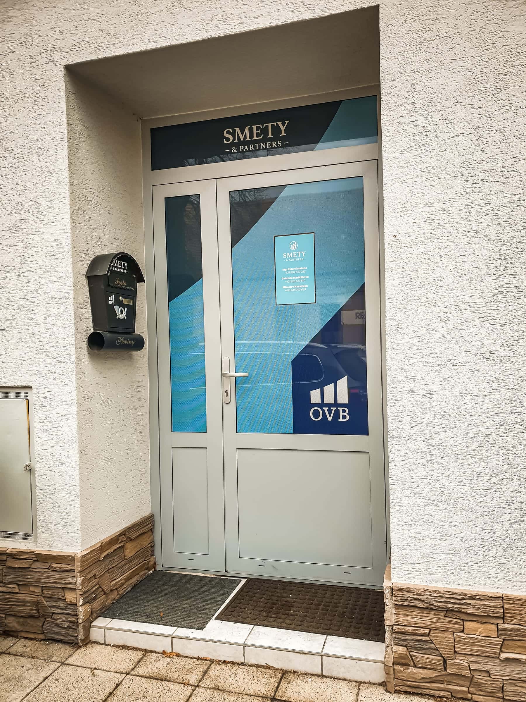 Vchod kancelárie SMETY & Partners s polepom dverí a nadsvetlíka a logom OVB