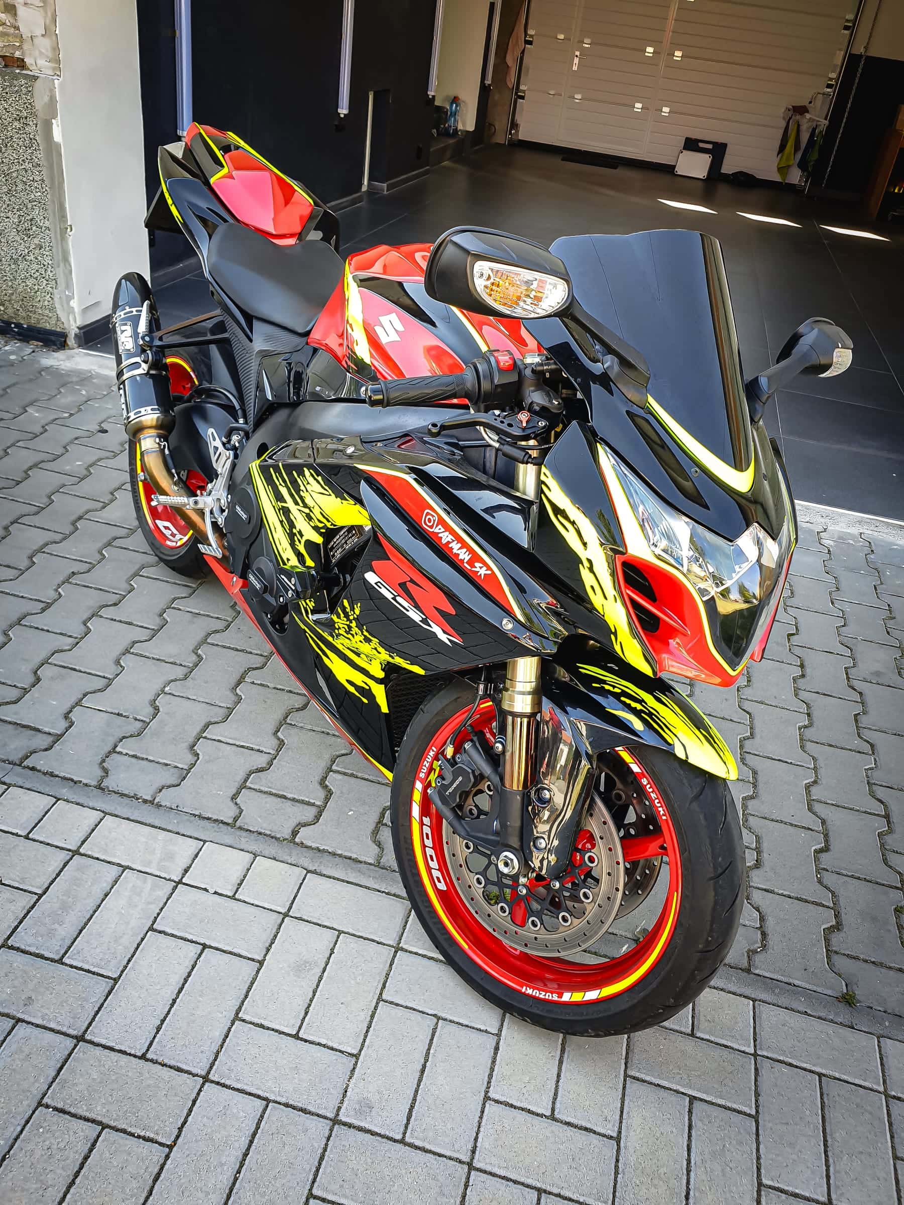 Motorka Suzuki GSX-R s čierno-červeno-žltým polepom a pruhmi na ráfikoch